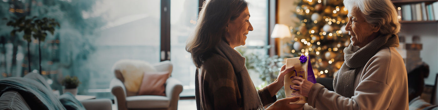 Gift Subscription hero -- woman receiving Coffee Bean Direct coffee gift with a Christmas tree in the background