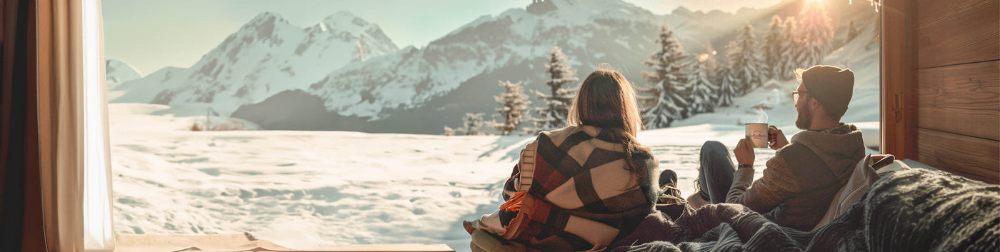 February Roaster's Blend featured hero -- man and woman sitting inside  watching a snowy mountain landscape while drinking coffee